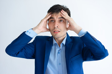 Stressed young business man touching head. Handsome guy thinking hard. Stress concept. Isolated front view on white background.