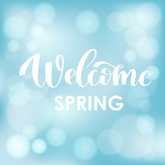 Naklejka na ściany i meble Welcome Spring. Hand drawn calligraphy and brush pen lettering on light blue sky blured background with bokeh.