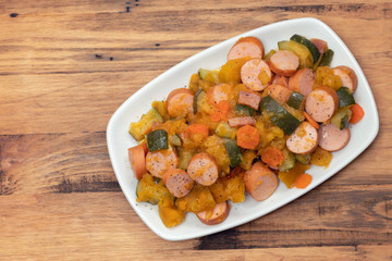 stew sausages with sweet potato and vegetables on white dish