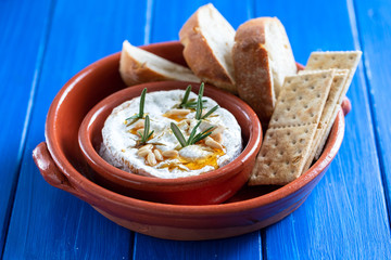 cheese camembert with nuts and rosemary in ceramic dish