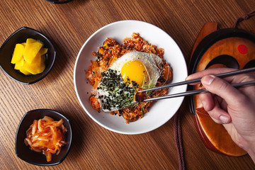 Male hand holds Chinese food with chopsticks. Top view on traditional chinese cuisine. Restaurant, food menu, recipe, cafe concept. Lifestyle food Korean cuisine. Local food. Free copy space