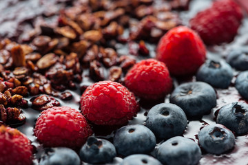selective focus of blueberries, raspberries and granola in smoothie bowl