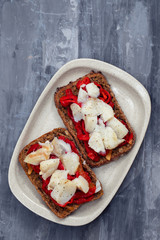 black healthy bread with cod fish and red pepper on dish
