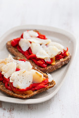 black healthy bread with cod fish and red pepper on dish