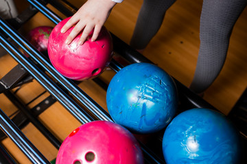 Close-up on teen children hand holding bowling ball against bowling alley - Image. Cheerful Kids are  ready to play - Image.  The bowling alley return machine system concept copy space design