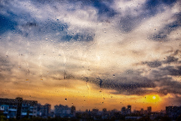 Fototapeta premium Water droplets on a window pane with beautiful defocused scenery outside.