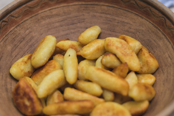 Sticks of dough and potatoes fried to crust in a wooden bowl