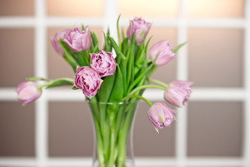 Beautiful spring flowers in vase on window background