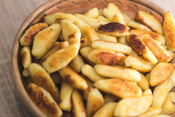 Sticks of dough and potatoes fried to crust in a wooden bowl