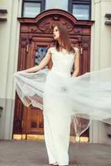 Obraz premium Gorgeous elegant caucasian young lady posing outdoors in old town in fashionable wedding dress. Beauty, fashion, vogue concept