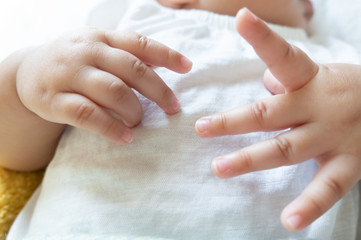 Newborn baby hands on a white shirt, baby hands and nails
