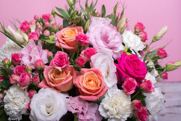 beautiful floral arrangement in the box, pink and yellow rose, pink eustoma, green and pink chrysanthemum, white carnation, pink dahlia on pink background with space for text.