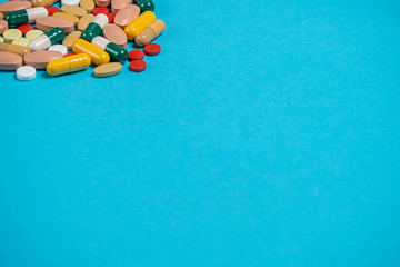 .scattered multicolored pills on a blue background with a place for copy space