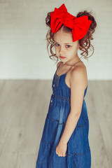 Fashionable close up portrait of young teen girl in jeans dress with red bow