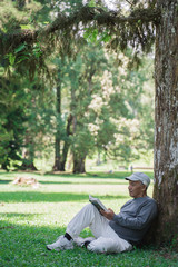 Obraz premium senior asian old man reading a book outdoor