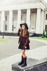 Fototapeta premium Outdoor portrait of teenage girl in stylish look, in black hat posing outdoors in park