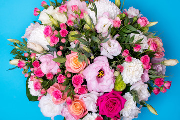 beautiful floral arrangement, pink and yellow rose, pink eustoma, green and pink chrysanthemum, white carnation, pink dahlia on a blue, turquoise background with space for text.