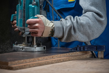 man with a mill works in safety glasses and headphones and a sparkler. the master produces wooden...