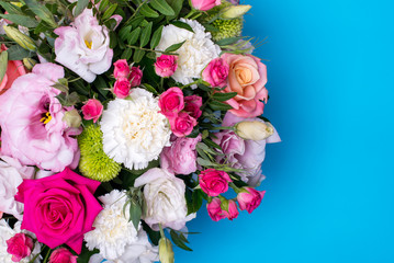 beautiful floral arrangement, pink and yellow rose, pink eustoma, green and pink chrysanthemum, white carnation, pink dahlia on a blue, turquoise background with space for text.