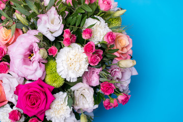 beautiful floral arrangement, pink and yellow rose, pink eustoma, green and pink chrysanthemum, white carnation, pink dahlia on a blue, turquoise background with space for text.