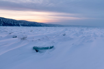 Obraz premium Winter landscape in pink tones with ridged ice on the frozen Lena river at sunset in the Natural Park Lenskie Stolby (Lena Pillars), Yakutia, Russia. Pano