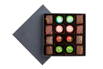 Assortment of luxury bonbons with colorful splashes in black box isolated on white background