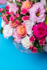 beautiful floral arrangement, pink and yellow rose, pink eustoma, green and pink chrysanthemum, white carnation, pink dahlia on a blue, turquoise background with space for text.
