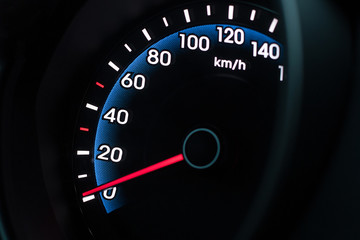 Speedometer with blue and white backlight with a needle at zero in the dark.