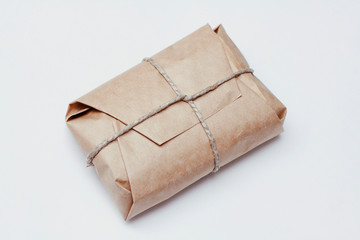 Box parcel wrapped in brown craft paper   tied hemp cord on white background. 