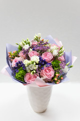 A bouquet of a large number of various natural flowers (color: white, pink, purple, green) paper packaging on a white background