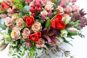 Fototapeta na wymiar Flower arrangement of bright fresh flowers of different varieties (colors: red, pink, white, green) in a white cardboard box on a bright background