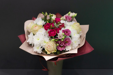 Bright bouquet of bright colors in paper packaging against a gray background.