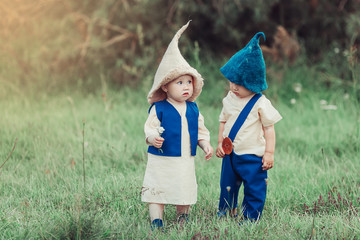 Little infant cheerful caucasian baby boy and baby girl in gnome costume's together in forest. CHildhood, infant, adorable, fairy tale concept