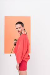 beautiful stylish girl looking at camera, holding rose and posing with living coral on background