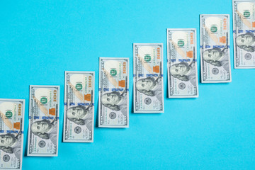 .hundred dollar banknotes on a blue background with a rise in the rate