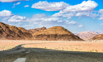 Kings highway, beautiful curvy road running through the Wadi Rum desert with rocky mountains in the distance, Jordan.