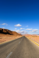 Kings highway, beautiful curvy road running through the Wadi Rum desert with rocky mountains in the distance, Jordan.