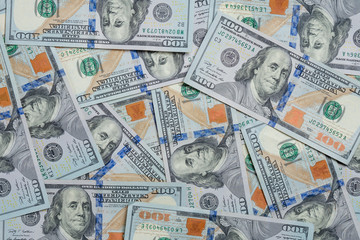 many hundred-dollar banknotes are chaotically scattered on the table