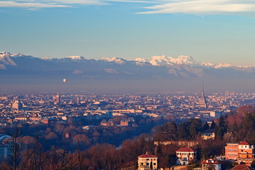 Panorama of Turin at dawn, overlooking the city center and the Mole Antonelliana, a backdrop of snow-capped mountains illuminated by pink light