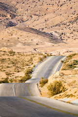 Kings highway, beautiful curvy road running through the Wadi Rum desert with rocky mountains in the distance, Jordan.