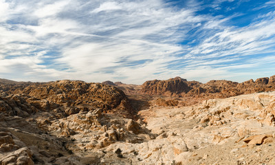 Fototapeta na wymiar Amazing view of a beautiful canyon in Petra with rocky mountains in distance. Petra is a Unesco World heritage site, historical and archaeological city in southern Jordan.