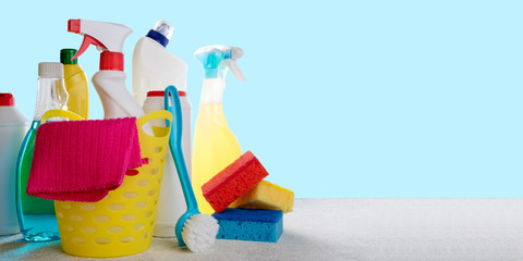 Basket with cleaning products on blue background. Cleaning with supplies, cleaning service concept. Copy space