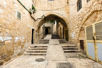 Fototapeta na wymiar Amazing view of a small alley surrounded by the walls of the Old city of Jerusalem, Israel. The Old City is a 0.9 square kilometres walled area within the modern city of Jerusalem.