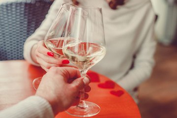Female and male hands clinking with two glasses of champagne (Prosecco) - date, love and Valentine’s Day celebration concept.