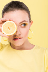 beautiful stylish girl holding lemon, biting lip and posing isolated on limelight