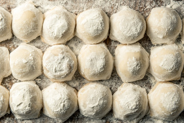 Fototapeta na wymiar Uzbek national food Chuchvara, like dumplings, on a wooden board, in flour