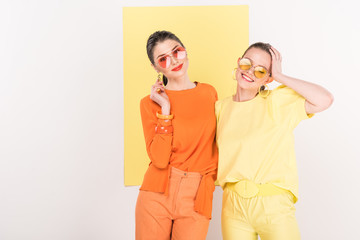 beautiful fashionable girls in sunglasses posing with limelight on background