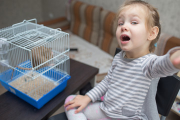 little beautiful girl child plays with a rat in a cage. Pets and children