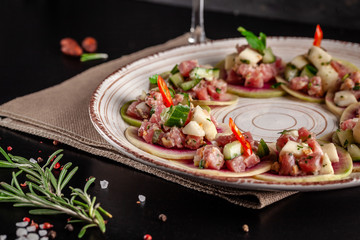 Concept of Spanish cuisine. Appetizer Tapas. Fresh tuna tartar, mussels, cucumber, apple, lemon, bitter, green onions, olive oil. Serving dishes in a restaurant on a ceramic plate. background image.