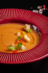 Concept of Spanish cuisine. Tomato soup Gazpacho from fresh tomatoes. Beautiful serving dishes in a red plate on a black table in a restaurant. background image. copy space